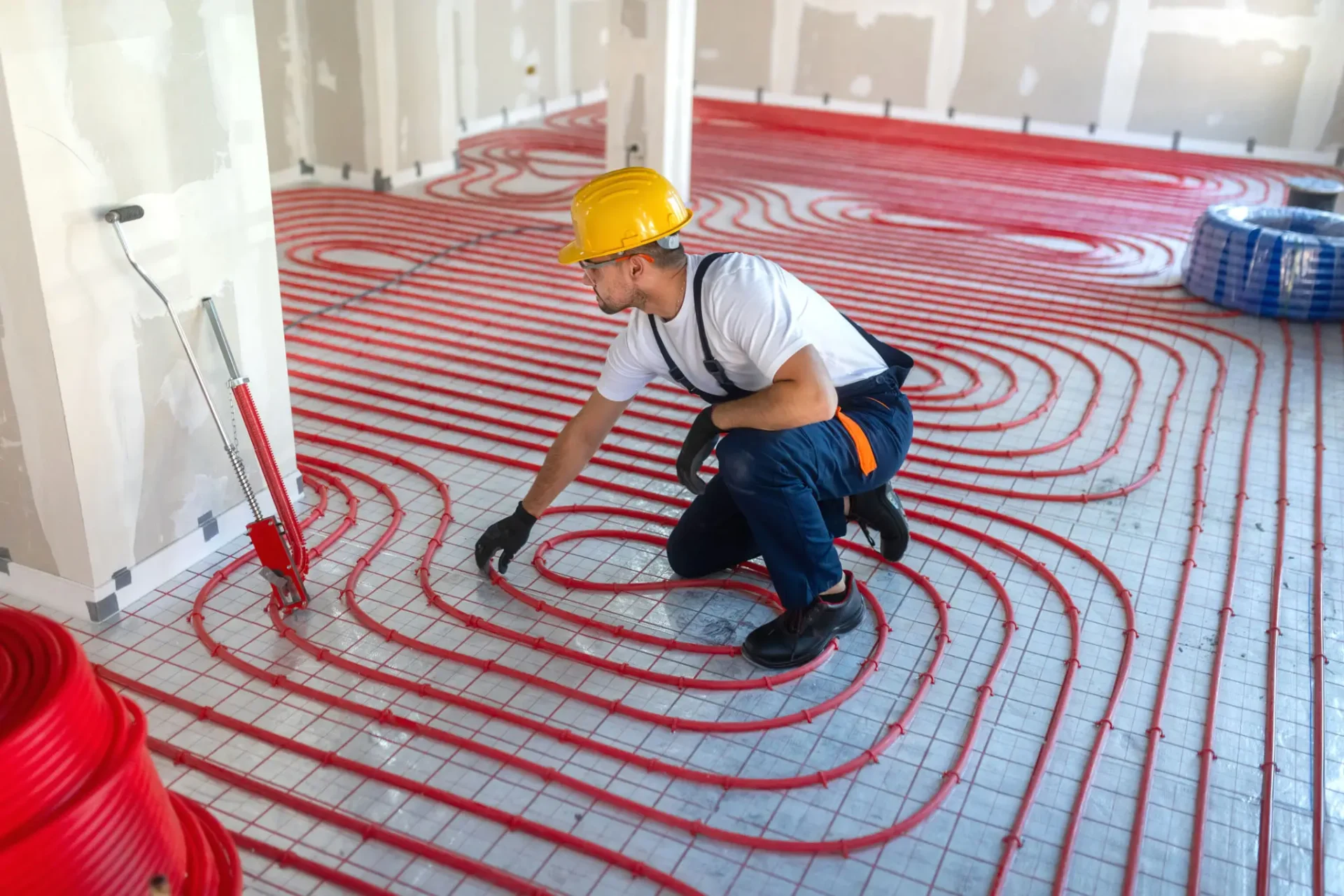 Worker installing red underfloor heating pipes