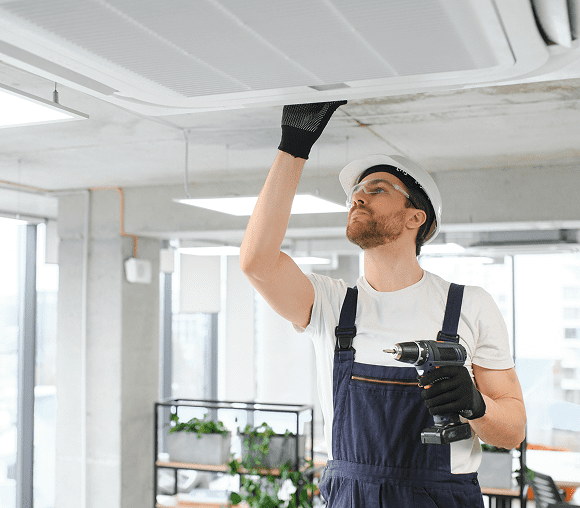 Technician fixing ceiling air conditioner unit