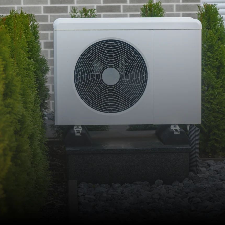 Outdoor air conditioning unit among green bushes
