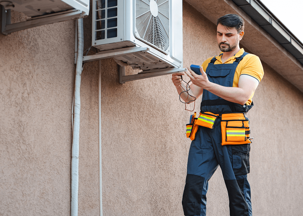 Worker inspecting AC unit with tools