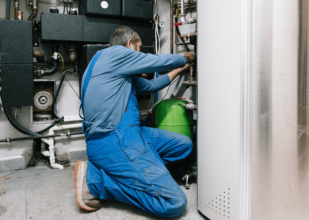 Plumber in blue overalls repairing system